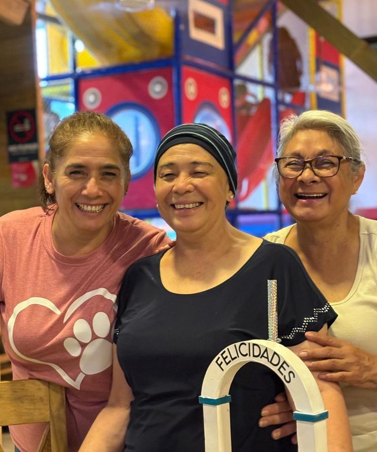 Tres mujeres de la fundación sonríen abrazadas durante una celebración